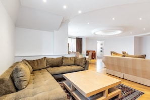 Ein modernes Wohnzimmer mit einem Ecksofa, einem zusätzlichen Sofa, einem Couchtisch und einem Essbereich mit Tisch und Stühlen.