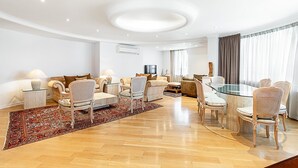 Ein modernes Wohnzimmer mit einem Glastisch, gepolsterten Sofas und einem gemusterten Teppich.