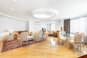 Ein modernes Wohnzimmer mit einem Glastisch, gepolsterten Sofas und einem gemusterten Teppich.