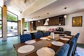 A modern kitchen with dark wooden cabinets, a large island, and pendant lighting.