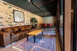 Un espace de détente moderne avec un mur en briques, une table basse en bois, un tapis à motifs et un canapé en cuir.