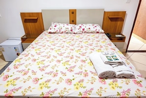 Une chambre d’hôtel comprenant un lit, une tête de lit en bois, des tables de chevet, un petit bureau et une imprimante.