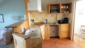 A compact kitchen with a sink, microwave, coffee maker, and wooden cabinets.