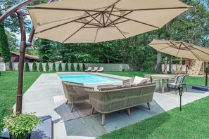 A backyard with a swimming pool, patio furniture, and umbrellas. - Summer Retreat: Private Jacuzzi, Game room & more (Centereach)