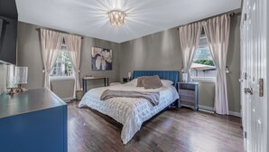 Een slaapkamer met een bed, nachtkastjes, een lamp, een schilderij en uitzicht op de omgeving.