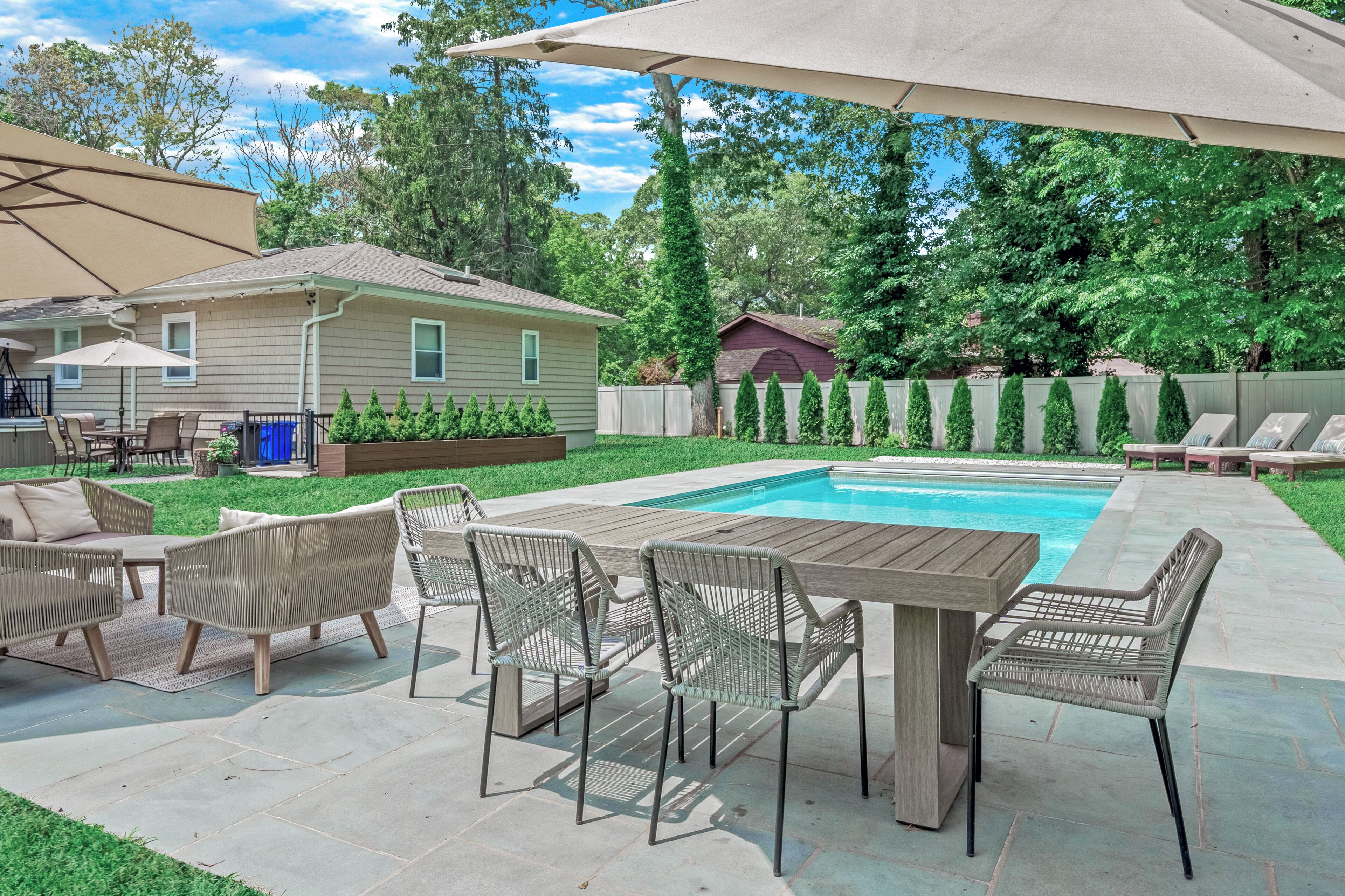 A backyard with a pool, outdoor furniture, and a covered patio area.