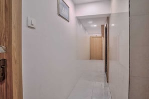 Ein Flur mit einer HolztĂŒr links, einem Lichtschalter und einem gerahmten Bild an der Wand.