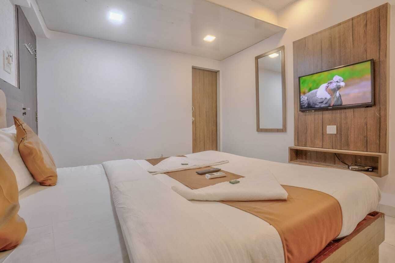 A hotel room with a bed, a television, a wooden wall panel, and a door.