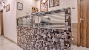 A reception area with a patterned wall, a glass partition, framed pictures, and a wooden door. - Hotel Sonal Inn (Mumbai)