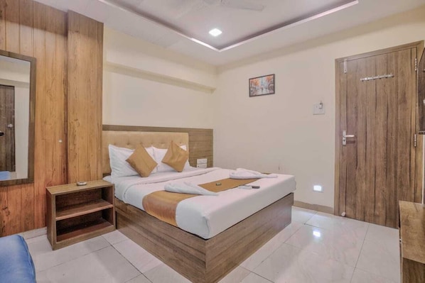 A hotel room with a wooden bed, a nightstand, a wardrobe, and a mirror. - Hotel Sonal Inn (Mumbai)