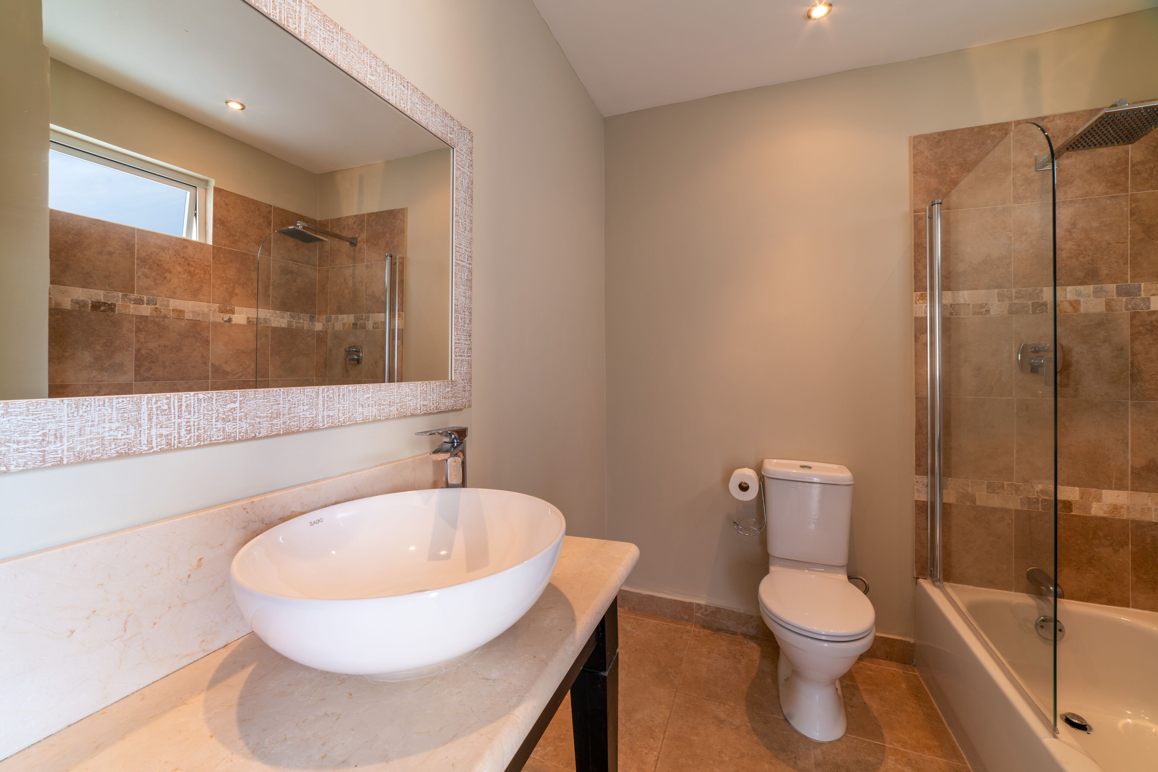 A bathroom with a large white sink, a toilet, and a glass-enclosed shower.