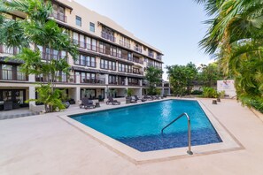 Ein Hotel mit Pool, Liegestühlen und Palmen.