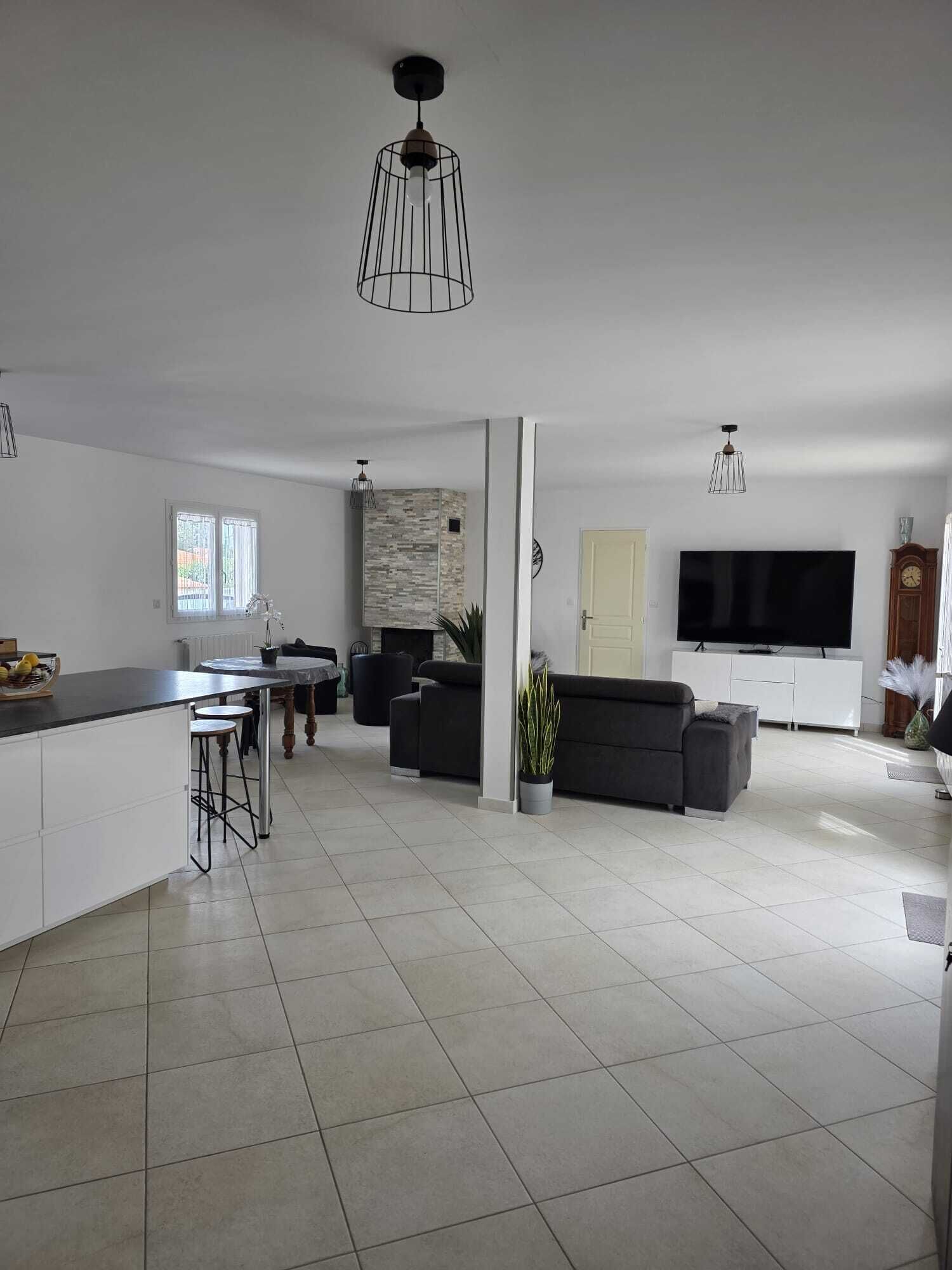 Uma sala de estar moderna com sofá, televisão e área de jantar.