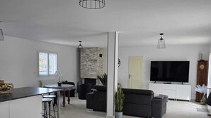 Un salon moderne avec un canapé, un téléviseur et un coin repas.