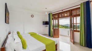 Una habitación con dos camas, televisión, balcón con cortinas y vistas al verdor.