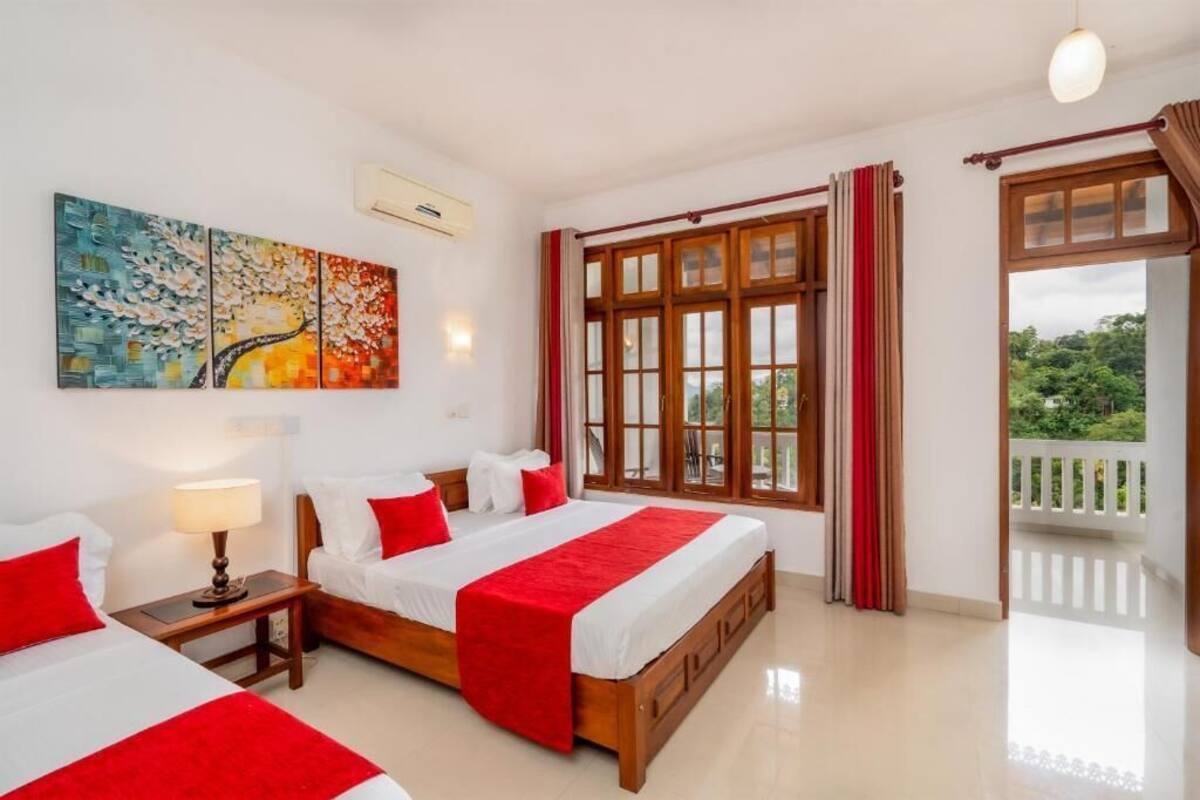 Habitación de hotel con dos camas, un cuadro, un ventanal con cortinas y un balcón.