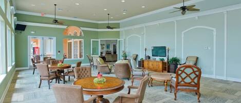 A spacious indoor area with multiple seating arrangements, ceiling fans, and a television.