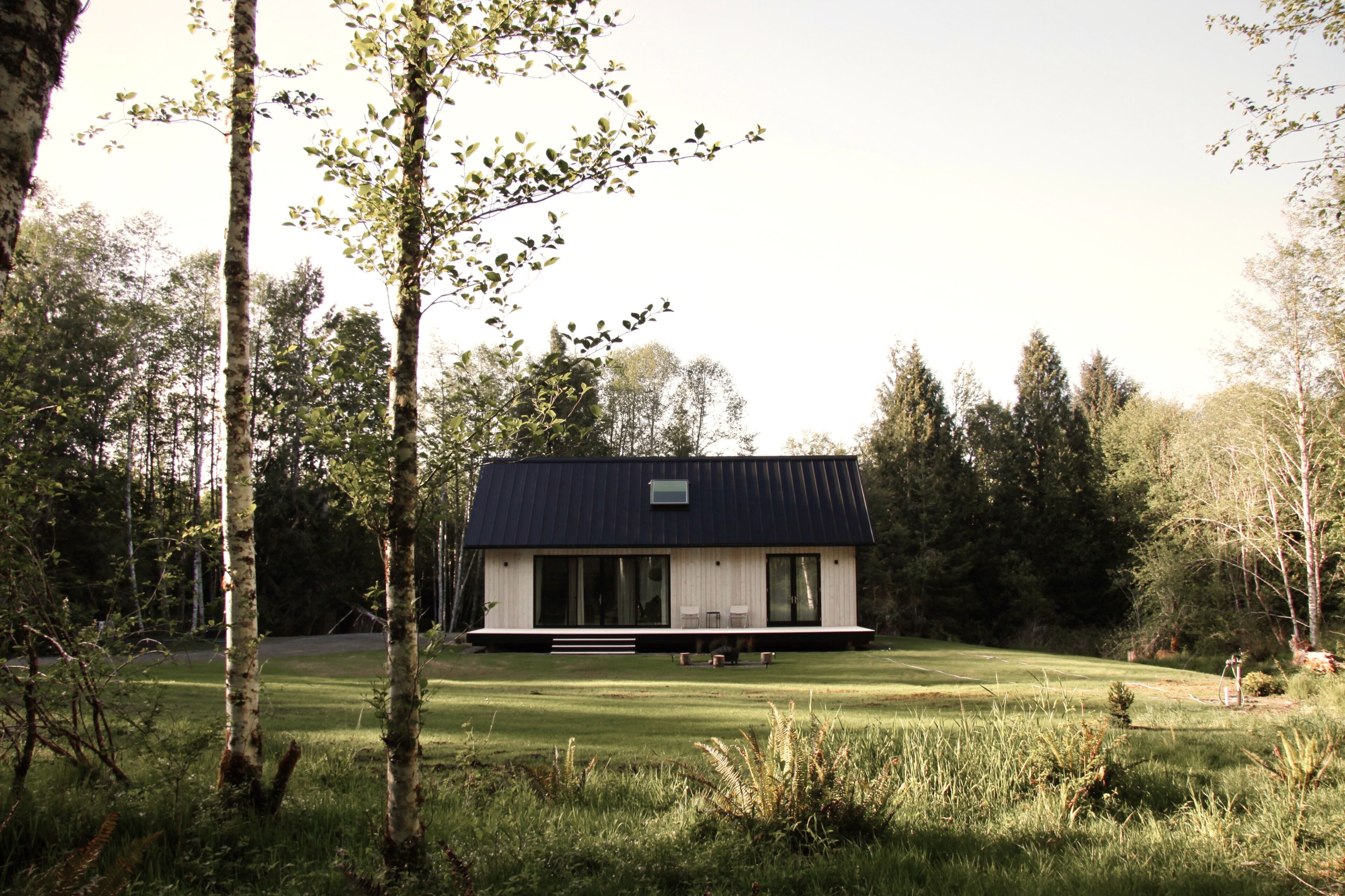 Een modern huis met een plat dak, grote ramen en een gazon.
