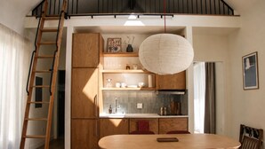Une cuisine moderne avec des meubles en bois, une table à manger avec des chaises, un luminaire suspendu et une échelle en bois.