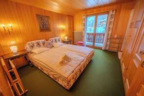 A wooden-paneled bedroom with a bed, bedside lamps, a radiator, a window with a view of a balcony, and a wooden ladder. - Domaine de l'Exceptionnel - 350 m² - 5 Suites (Ormont-Dessous)