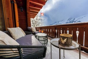 A wooden deck with outdoor seating, a flag, and a snowy mountain backdrop. - Domaine de l'Exceptionnel - 350 m² - 5 Suites (Ormont-Dessous)