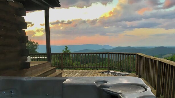 Un jacuzzi en una terraza de madera con vista a las montañas.
