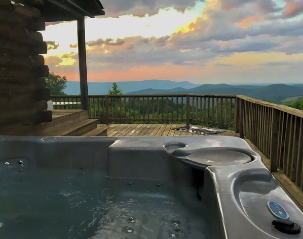 Un jacuzzi en una terraza de madera con vista a las montañas.