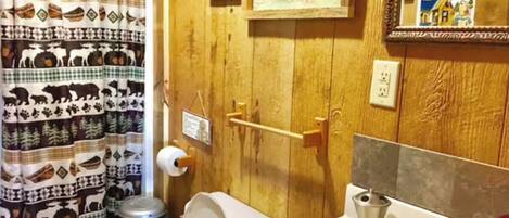 A bathroom with a wooden door, a toilet, a sink with a mirror, and a shower curtain with animal prints.