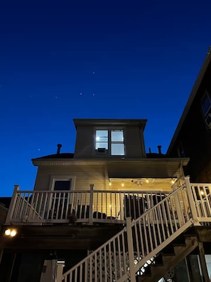 Ein zweigeschossiges Haus mit Balkon, Treppe und Veranda mit Lichterkette.