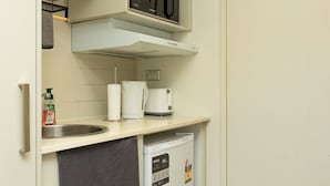 Eine kleine Küchenzeile mit Mikrowelle, Kaffeemaschine und kleinem Kühlschrank.