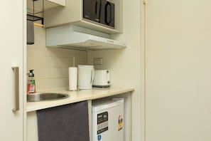 A compact kitchenette with a microwave, coffee maker, and a small refrigerator.