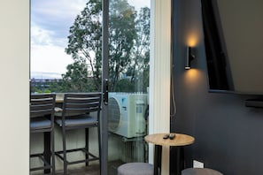 A balcony with a table, chairs, and an air conditioning unit.