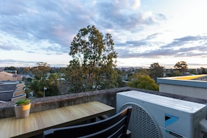 A rooftop terrace with a table, chairs, and an air conditioning unit.