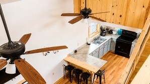 Una cocina compacta con armarios de madera, una mesa de comedor con sillas y un ventilador de techo.