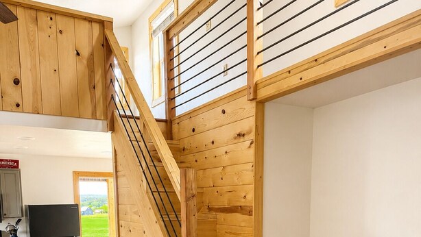 Una escalera de madera en un interior moderno con cocina y sofá.