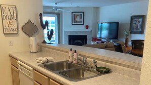 A kitchen with a double sink, a dishwasher, and a large mirror reflecting the living room. - Charming 2 bedroom lakefront condo with access to 3 outdoor pools in Osage Beach (Osage Beach)