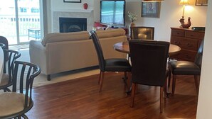 A living room with a fireplace, a dining area with a table and chairs, and a television. - Charming 2 bedroom lakefront condo with access to 3 outdoor pools in Osage Beach (Osage Beach)