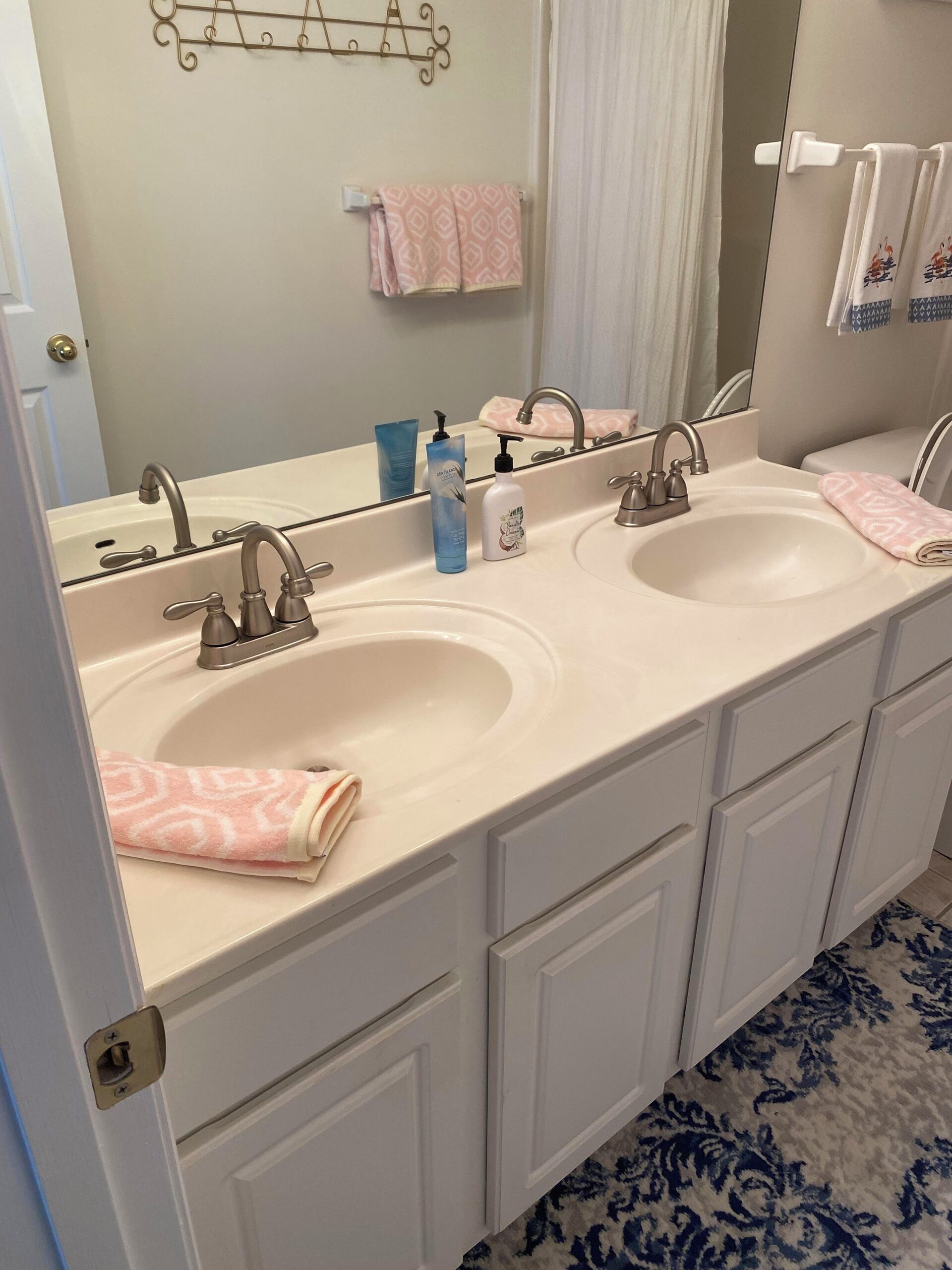 A bathroom with two sinks, a mirror, and a towel rack.