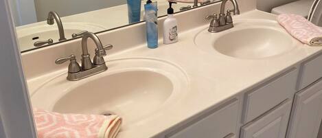 A bathroom with two sinks, a mirror, and a towel rack.