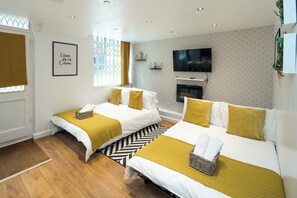 Et hotelværelse med to senge, fjernsyn, pejs og et vindue med gardiner.