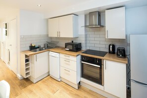 A modern kitchen with white cabinets, a dishwasher, a microwave, a toaster, and a coffee maker. - Central London Gem | Sleeps 8 | Hyde Park | London (London)