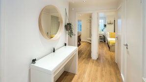 A modern bathroom with a white vanity, a round mirror, and a hanging plant. - Central London Gem | Sleeps 8 | Hyde Park | London (London)