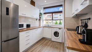 Eine kompakte Küche mit einem Edelstahl-Kühlschrank, einer integrierten Waschmaschine, einer Mikrowelle und einer Kaffeemaschine.