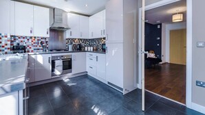 Een moderne keuken met witte kastjes, een roestvrijstalen afzuigkap en een betegelde spatwand.