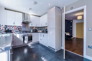A modern kitchen with white cabinets, a stainless steel range hood, and a tiled backsplash. - The Eastern Hive - 3x Parking | Co-op Live&Etihad (Greater Manchester)
