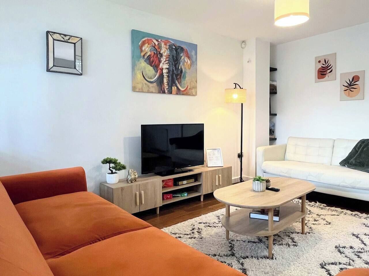 Ein Wohnzimmer mit Sofa, Couchtisch, Fernseher und einem Gemälde an der Wand.