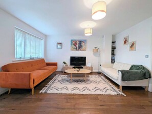 A living room with two sofas, a coffee table, a TV, and artwork on the walls.