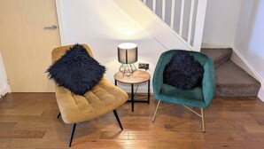 Een kamer met een houten vloer, een trap en twee stoelen met zachte kussens.