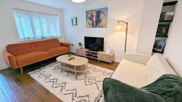 A living room with a sofa, a coffee table, a TV, and a lamp.