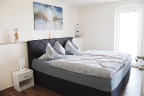 Een slaapkamer met een bed, nachtkastje en een schilderij aan de muur.